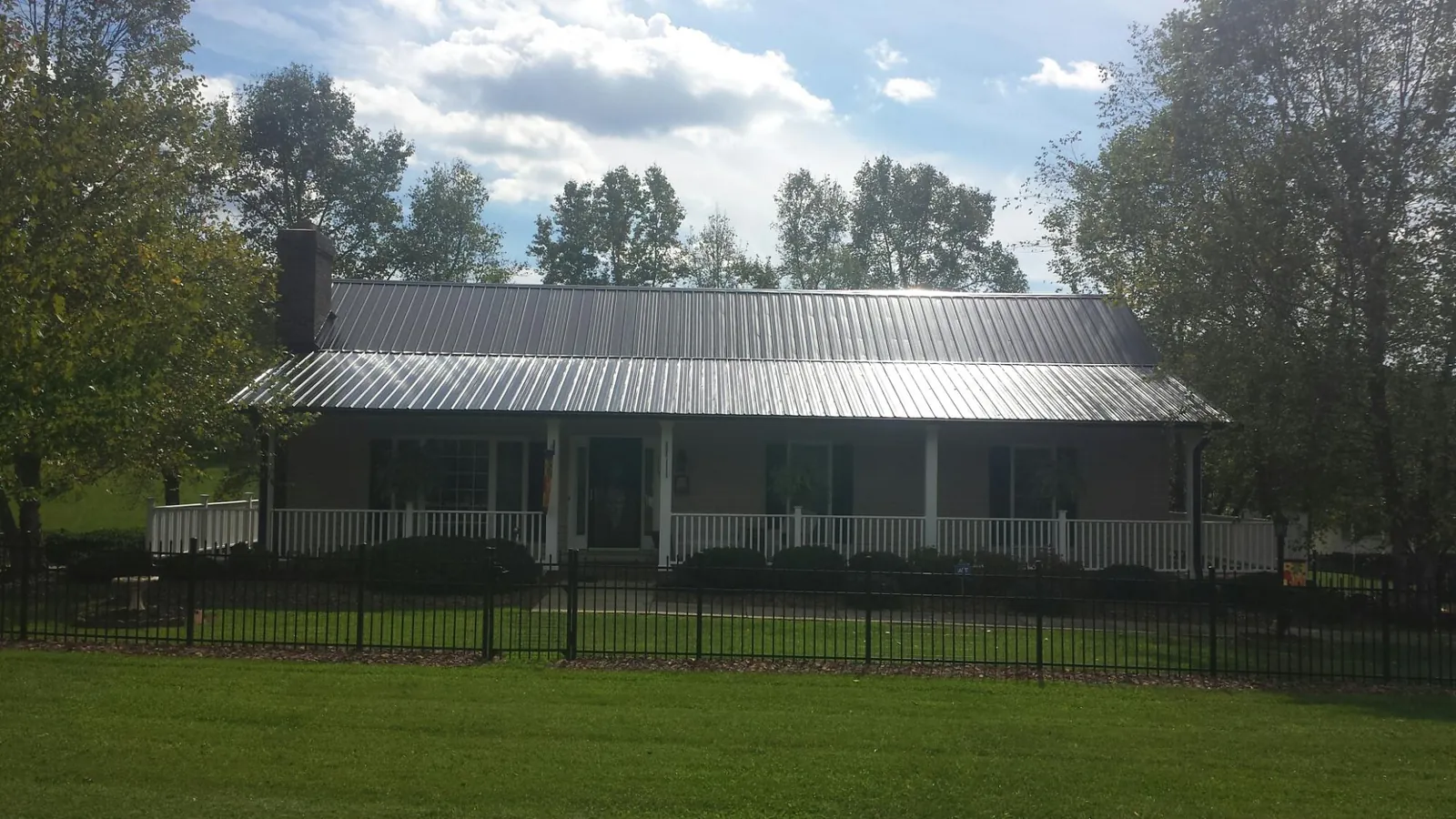 Gray metal roof on a brick ranch with a full width front porch — Gutter Guard Installation work by our crew in Pleasant Lake
